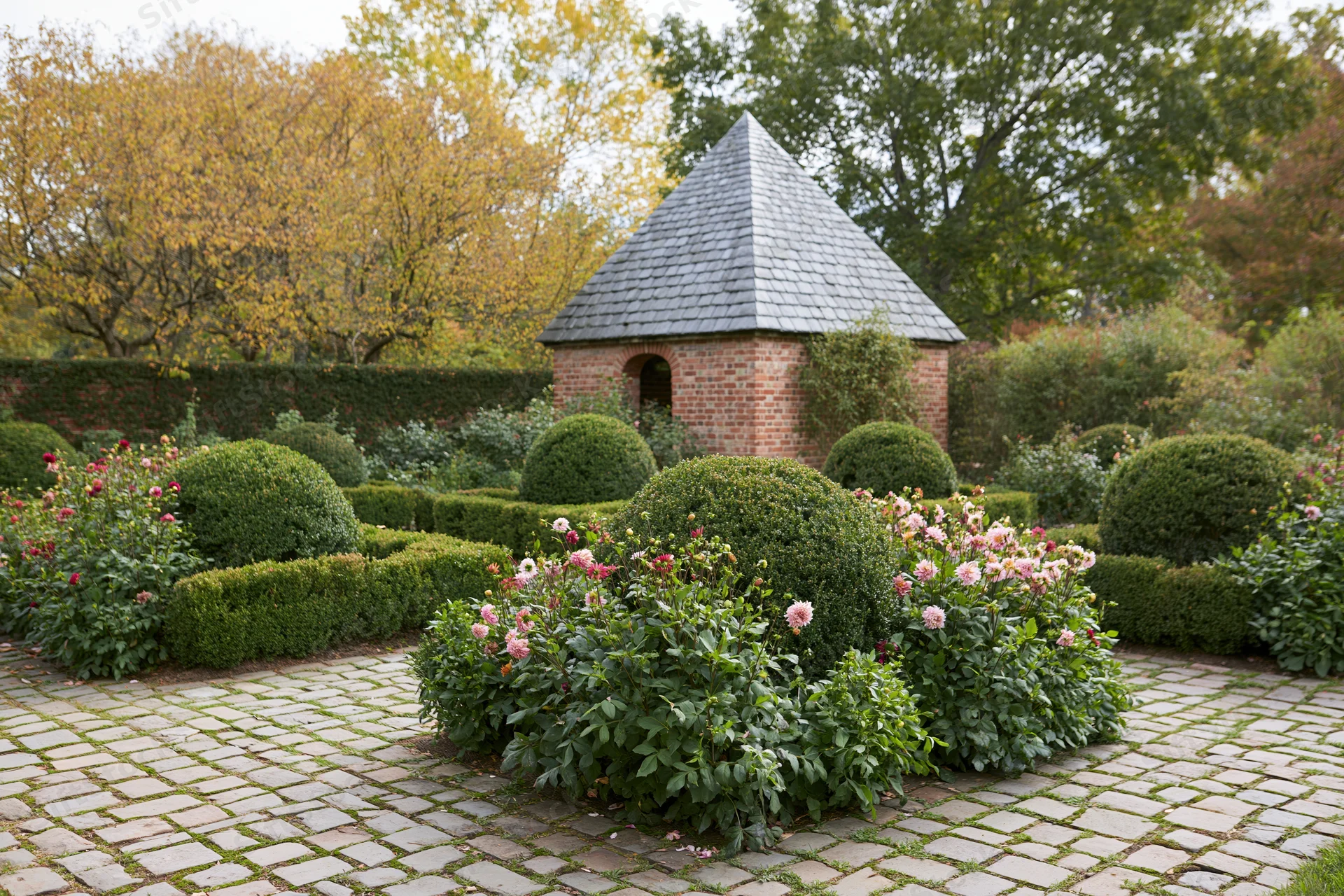 Formal european garden with brick gazebo and topiary hedges in early autumn