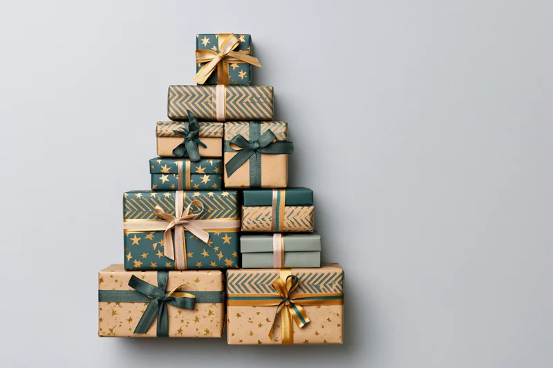 Gift boxes stacked in triangular christmas tree shape on plain background