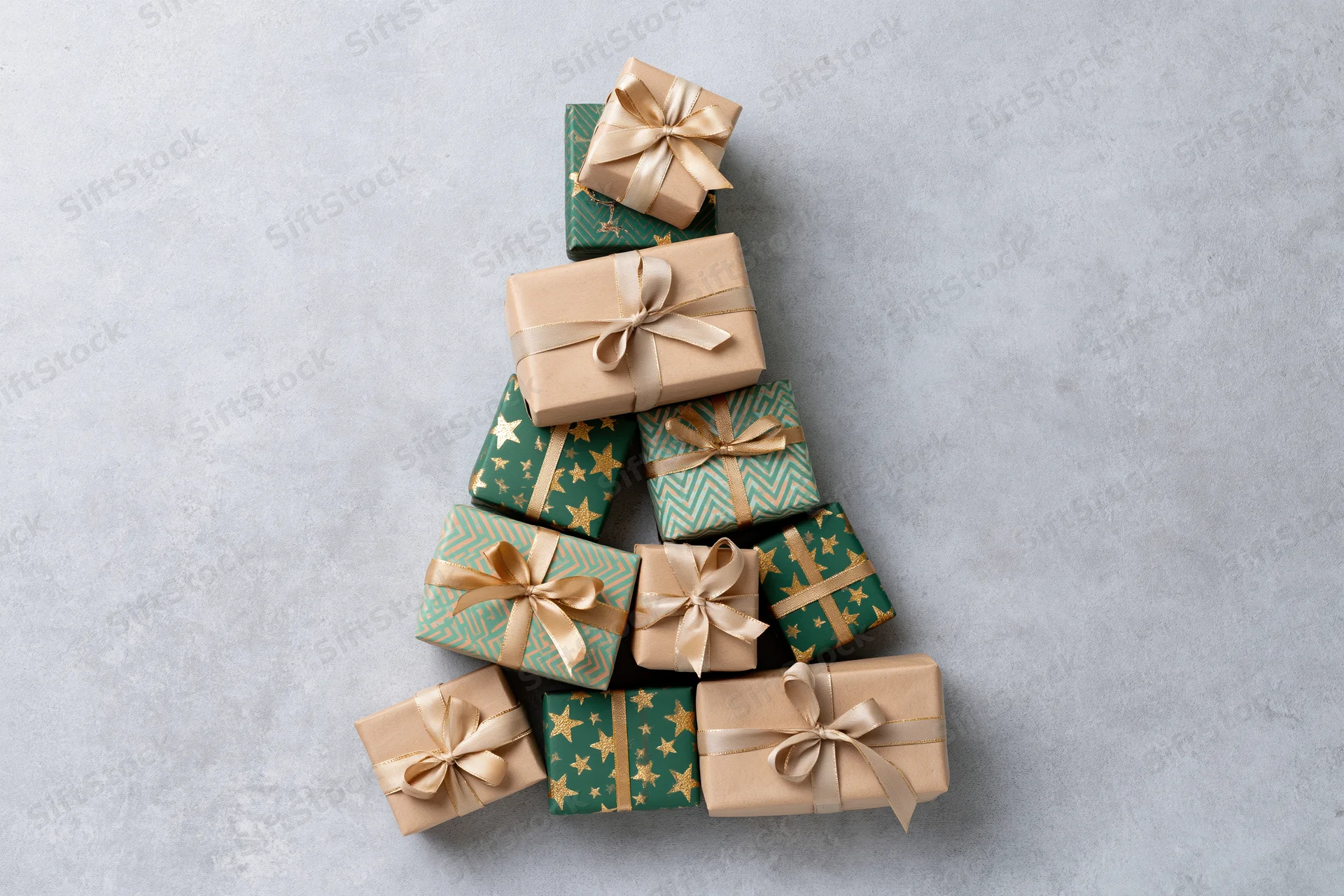 Gift boxes arranged in a triangular christmas tree shape on a light gray surface