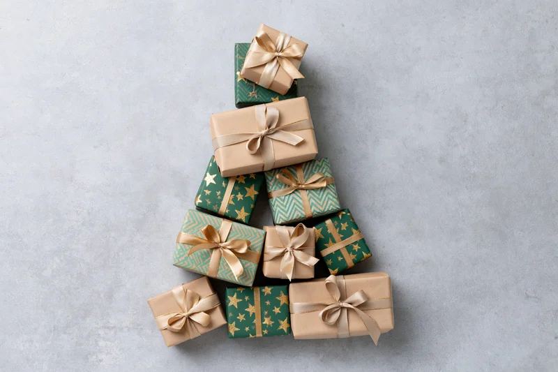 Gift boxes arranged in a triangular christmas tree shape on a light gray surface