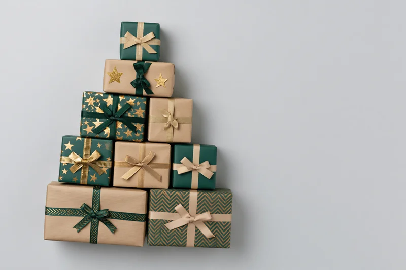 Gift boxes arranged in triangular christmas tree shape on plain background