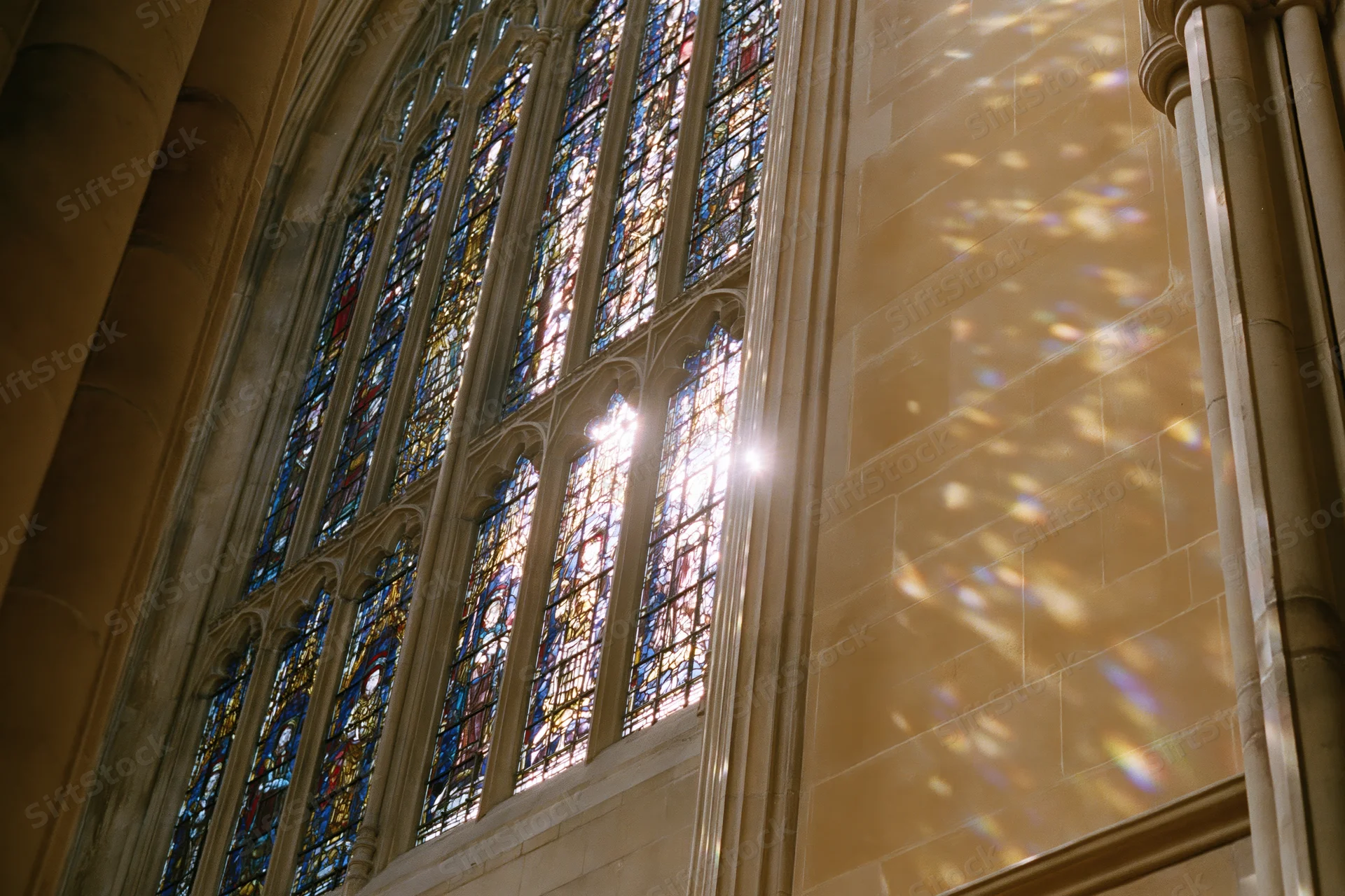 Sunlight streaming through large gothic stained glass window in cathedral interior