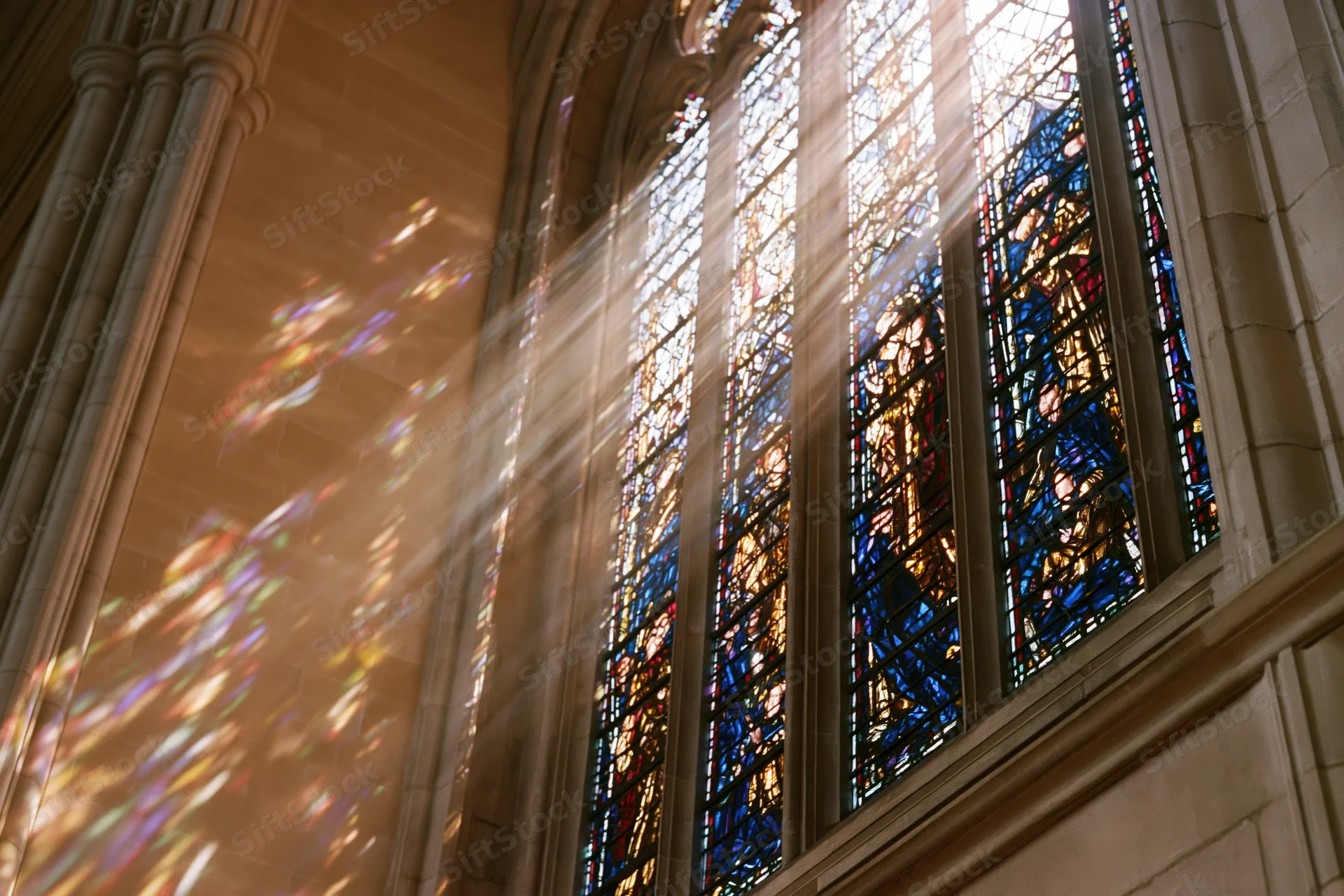 Sunlight streaming through stained glass window in gothic cathedral interior
