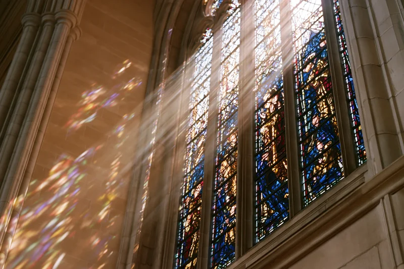 Sunlight streaming through stained glass window in gothic cathedral interior