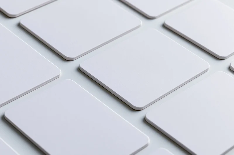 Blank white business cards with rounded corners arranged in a grid pattern on a light surface