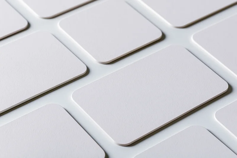 Blank white business cards with rounded corners arranged in a grid pattern on a flat surface