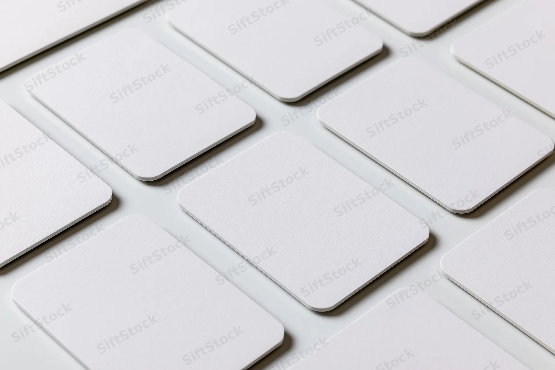 Blank white business cards with rounded corners arranged in a grid on a white surface