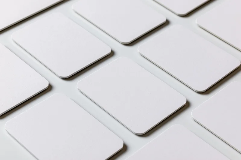 Blank white business cards with rounded corners arranged in a grid on a white surface