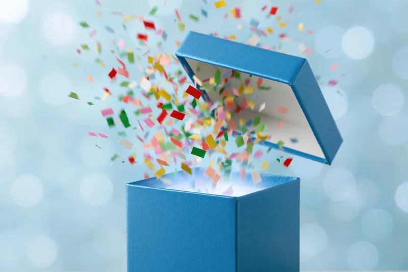 Blue gift box opening with confetti bursting out against a bokeh background