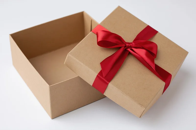 Open kraft cardboard gift box with red ribbon bow on white background