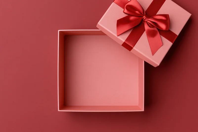 Open pink gift box with red satin bow on matching surface