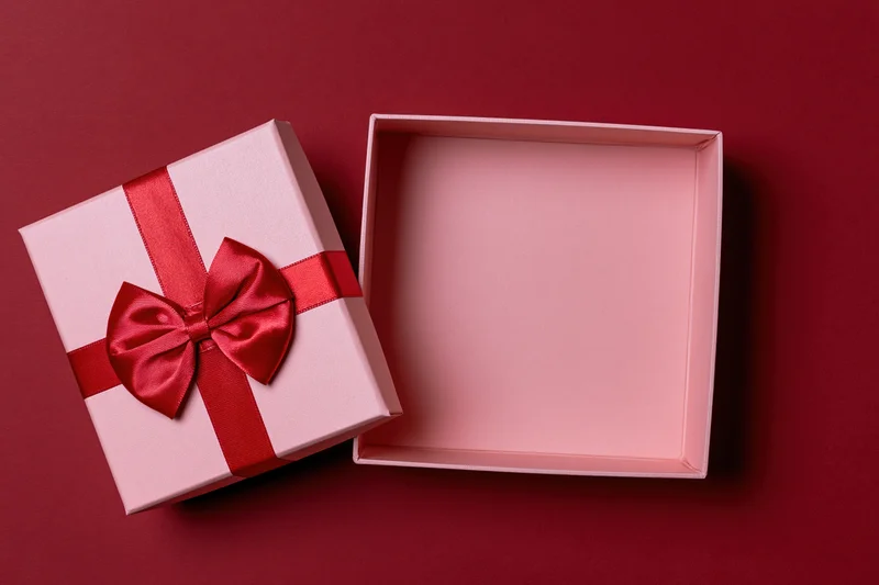 Open pink gift box with red satin bow on red background