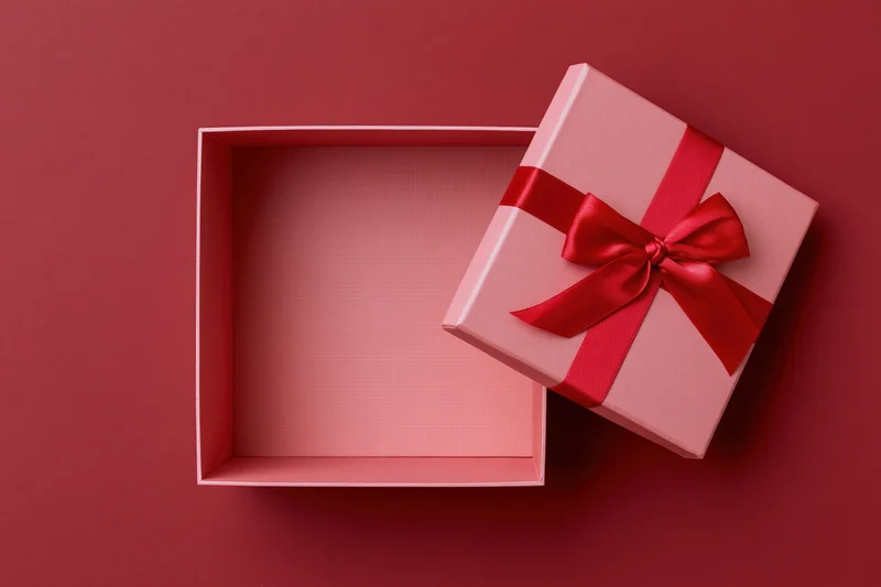 Open pink gift box with red satin bow on red surface