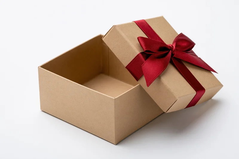Open kraft cardboard gift box with red ribbon bow on white background