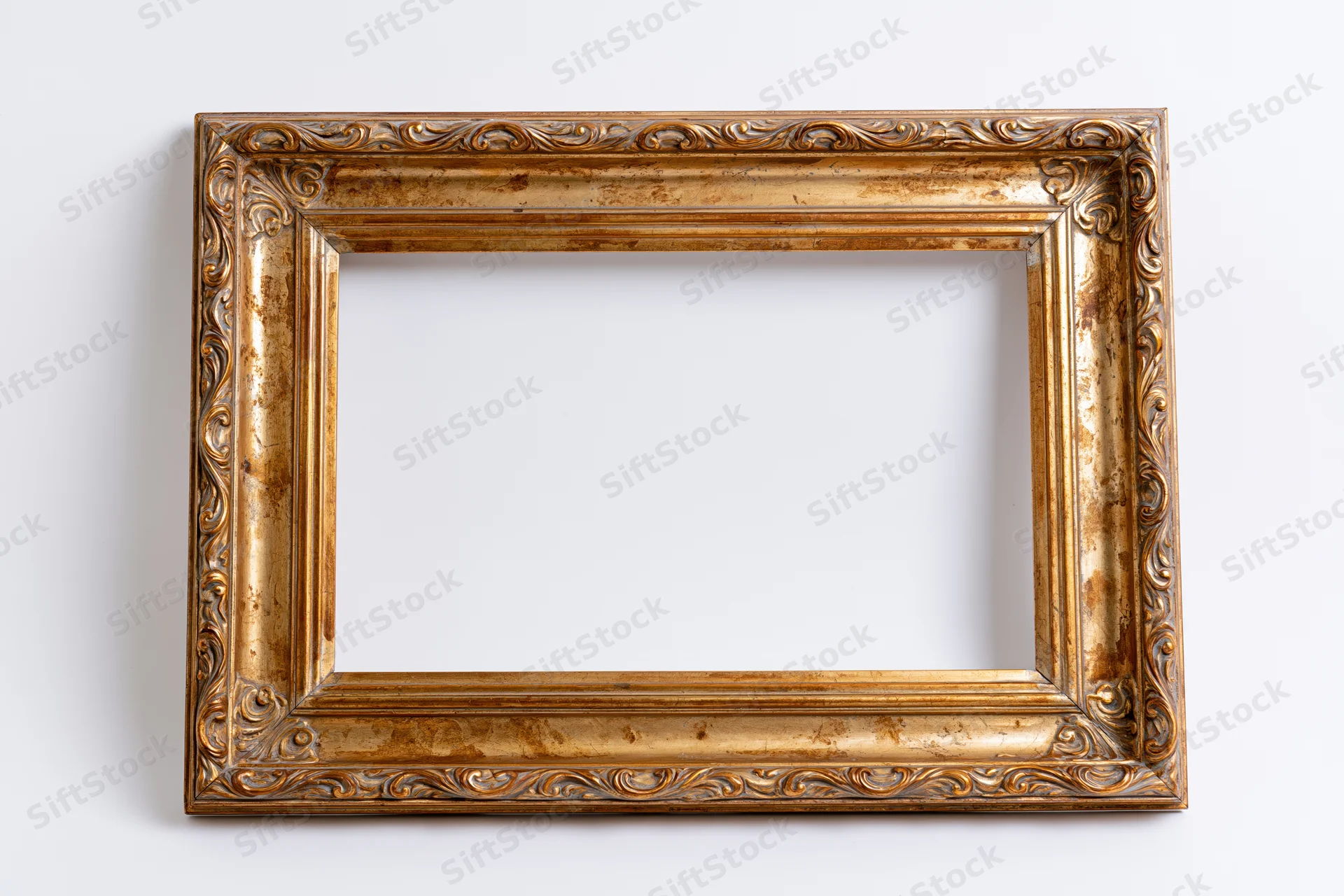 Ornate gold picture frame with aged finish hanging on white wall