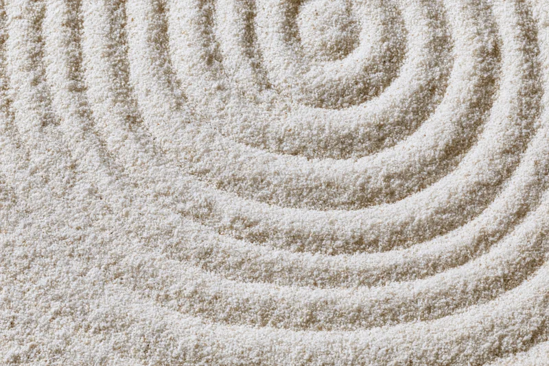 Raked sand surface with spiral pattern in a zen garden