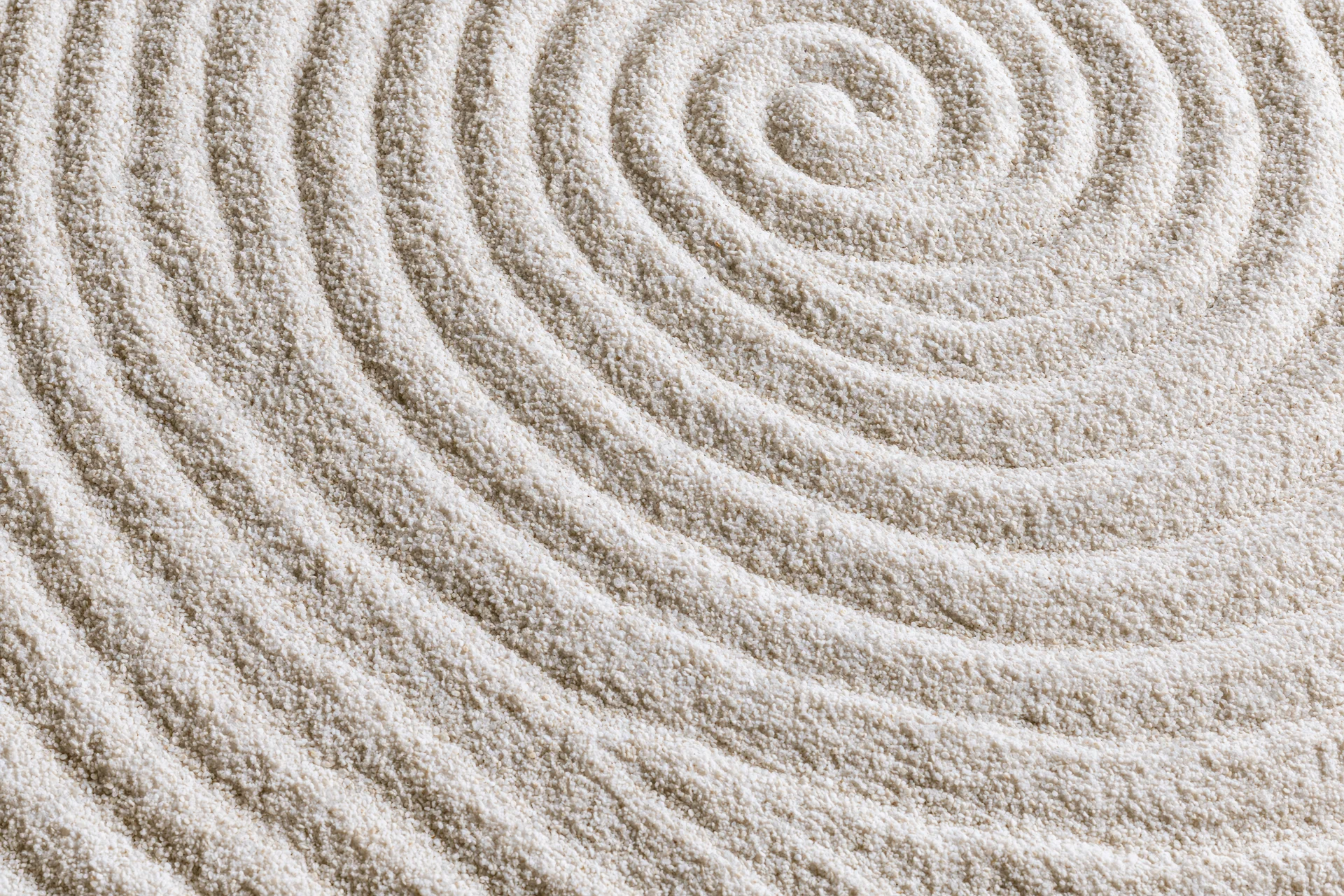 Raked sand surface with concentric spiral pattern in a zen garden