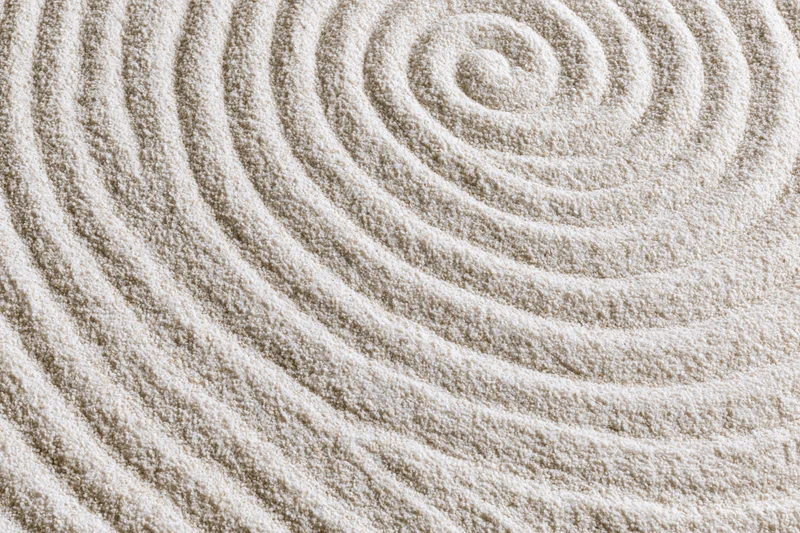 Raked sand surface with concentric spiral pattern in a zen garden