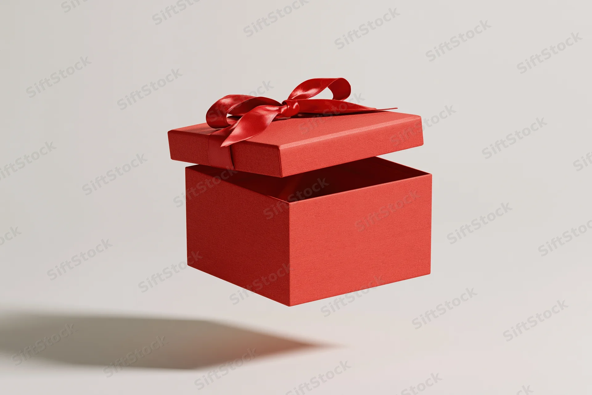 Red gift box with lid floating open and satin bow against white background