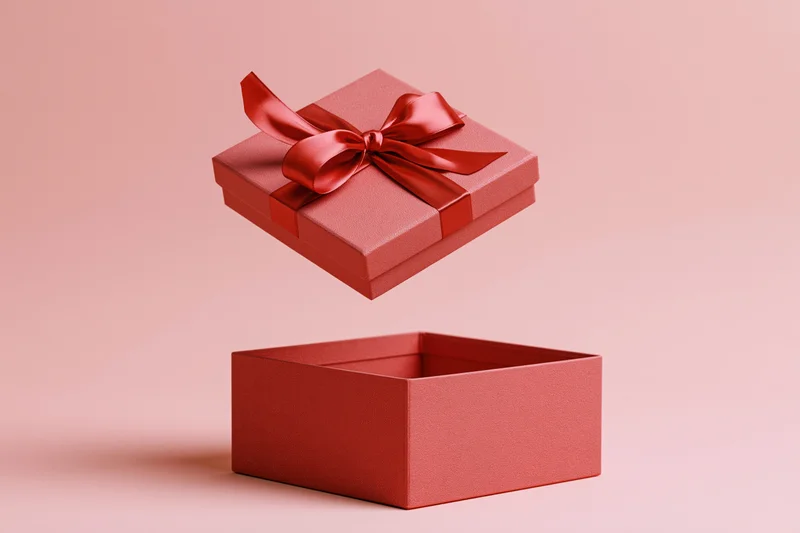 Red gift box lid floating midair with satin bow above open base on pink background