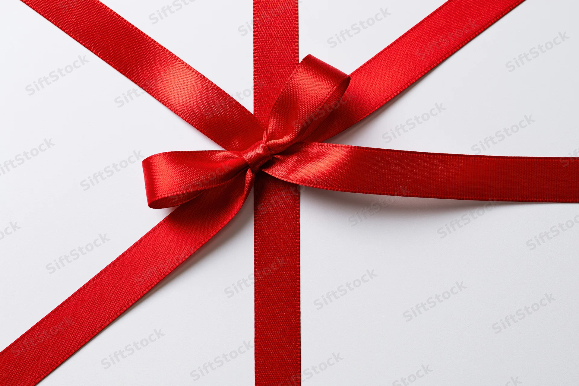 Red satin ribbon tied in a bow on white background with copyspace