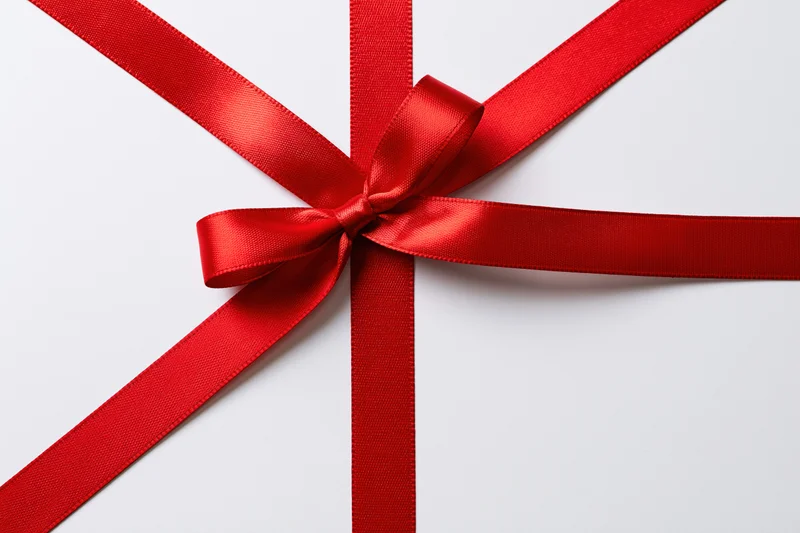 Red satin ribbon tied in a bow on white background with copyspace
