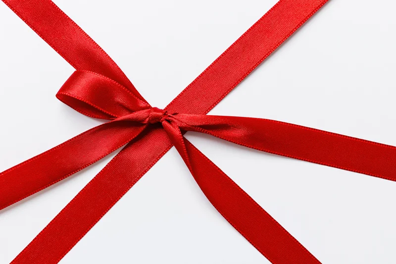 Red satin ribbon tied in a bow on white background with copyspace