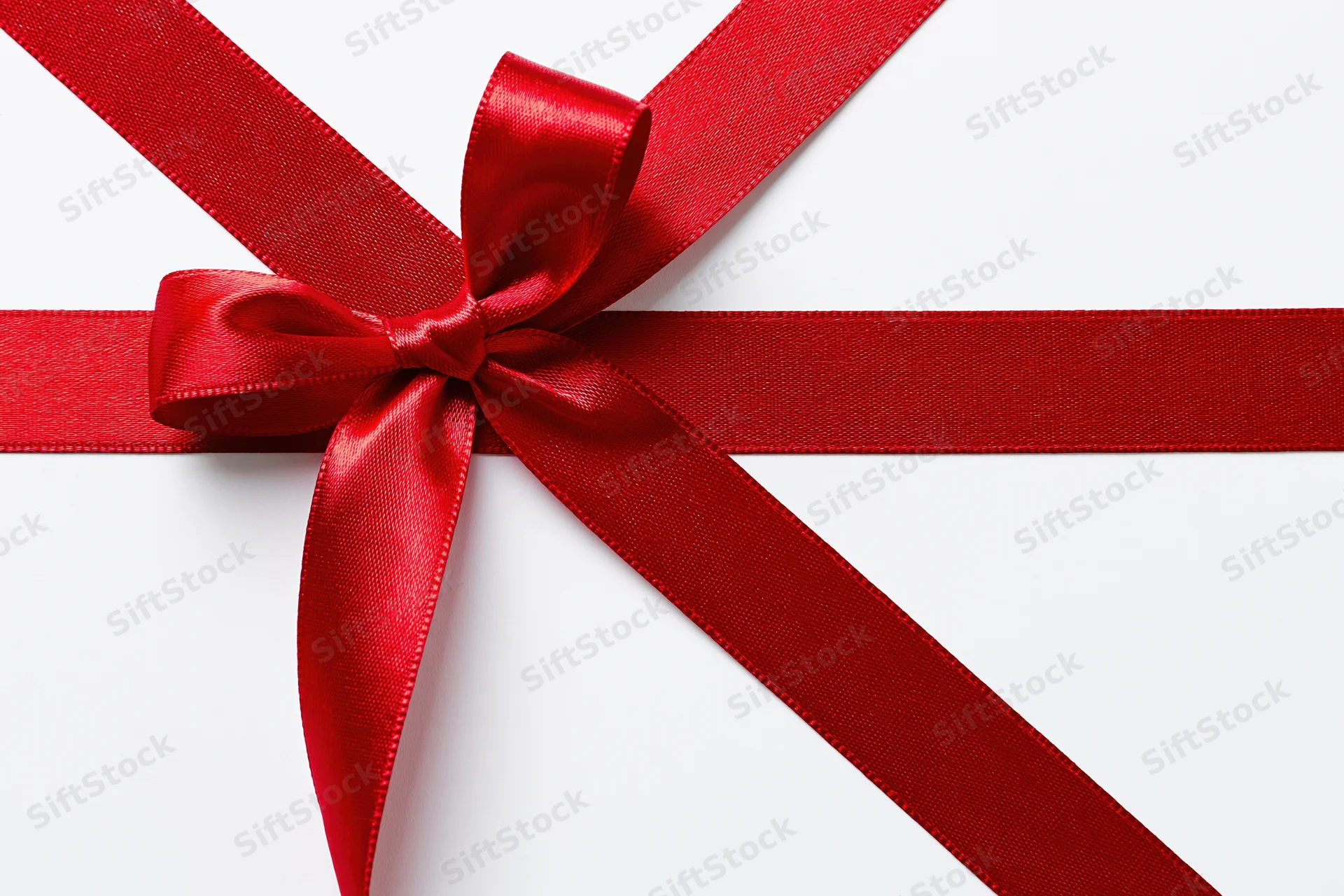 Red satin ribbon tied in a bow forming a cross on a white background