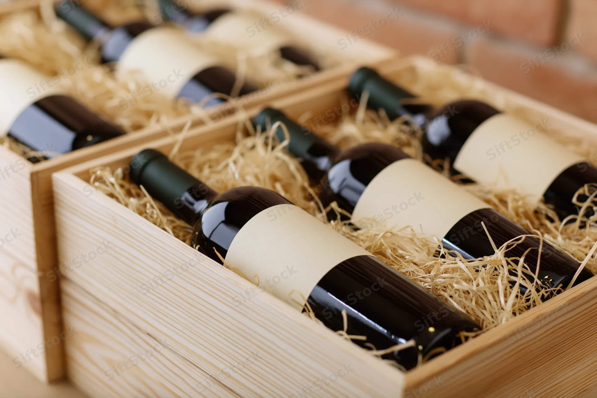 Red wine bottles lying on their sides in wooden crates filled with straw