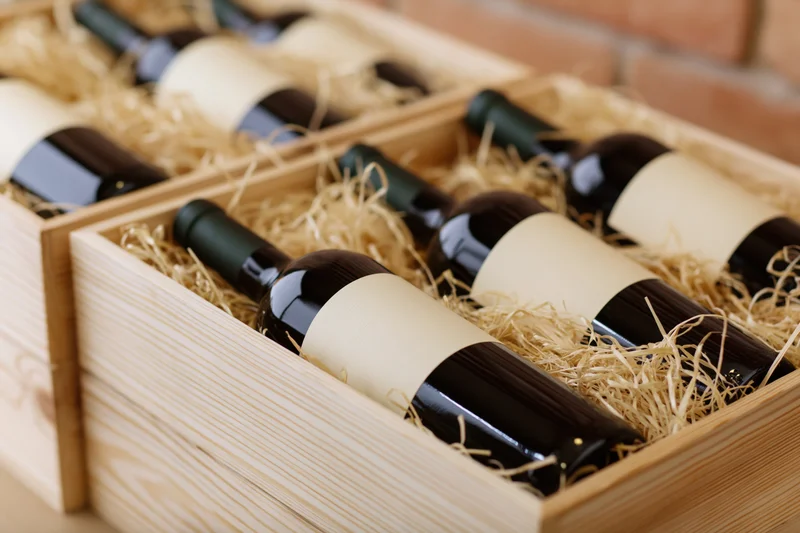 Red wine bottles lying on their sides in wooden crates filled with straw