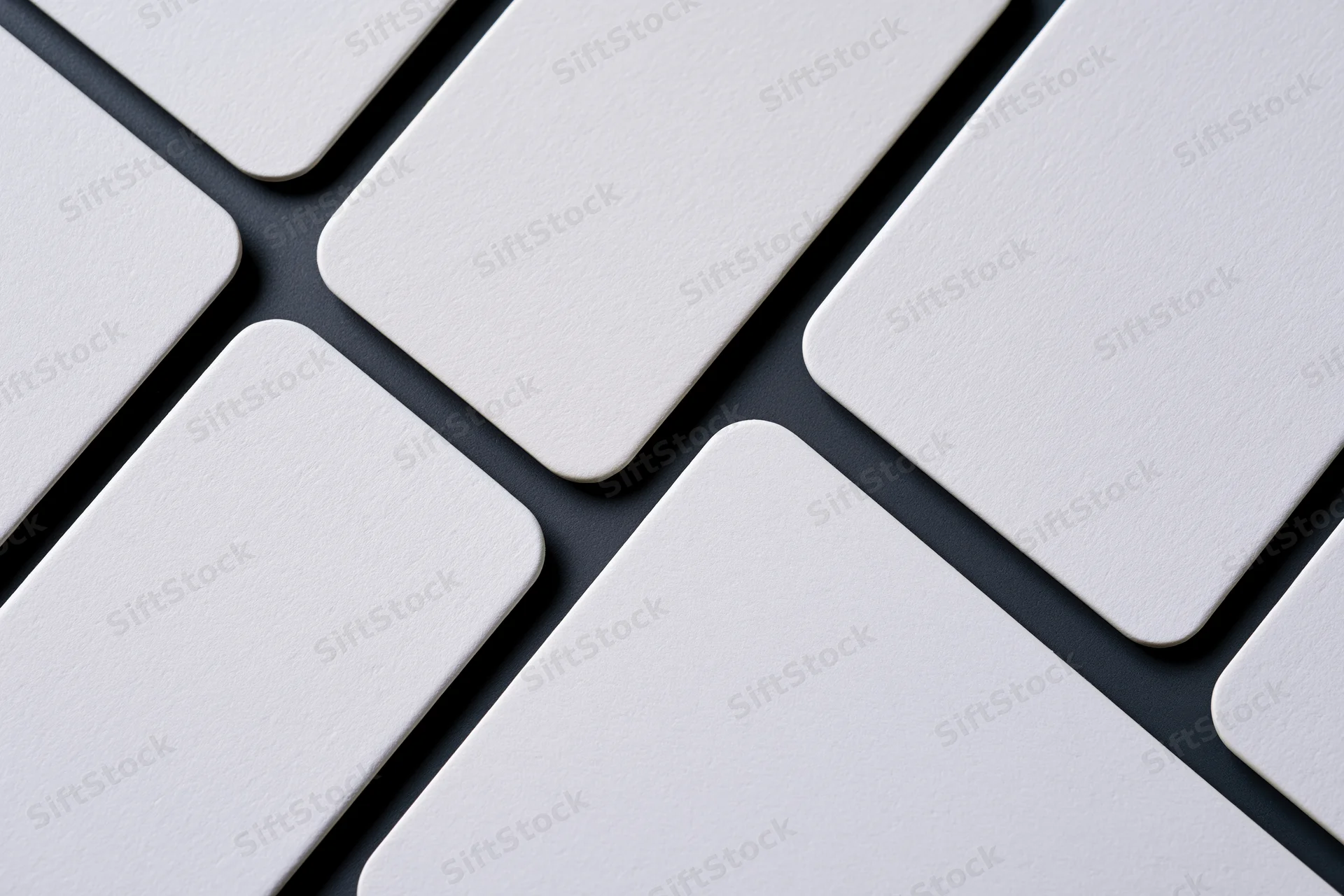 Blank white business cards with rounded corners arranged diagonally on dark surface