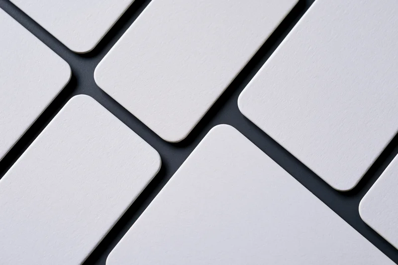 Blank white business cards with rounded corners arranged diagonally on dark surface