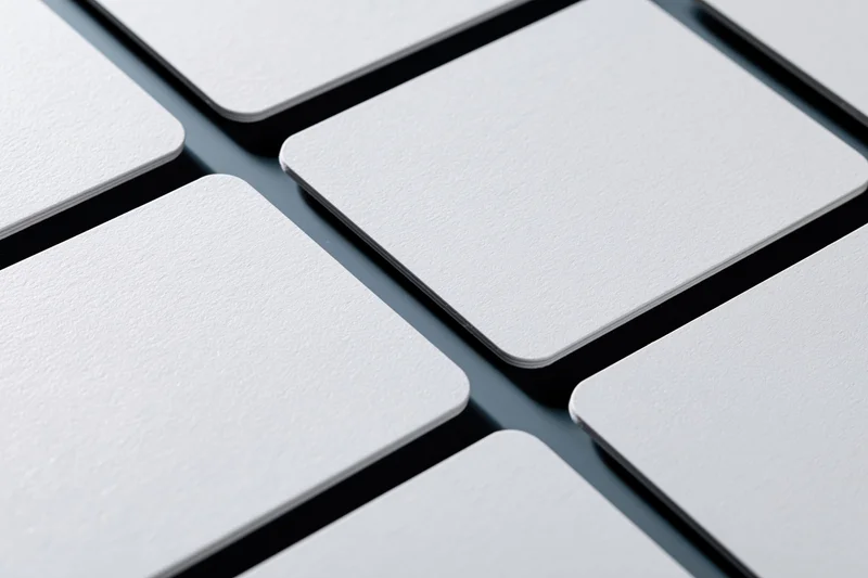 Blank white business cards with rounded corners arranged in a grid on dark surface
