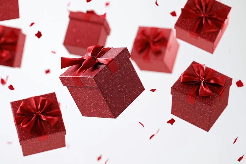 Red gift boxes with satin ribbon bows floating and tumbling against white background