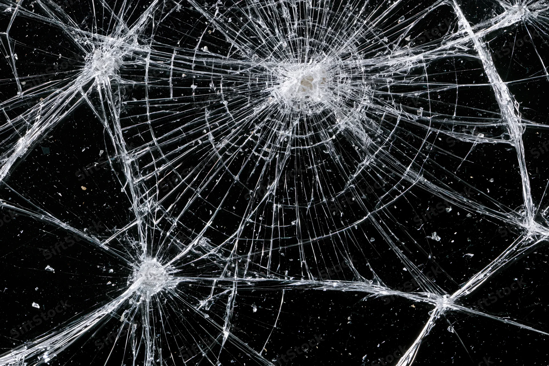 Shattered glass pane with radial cracks across black background