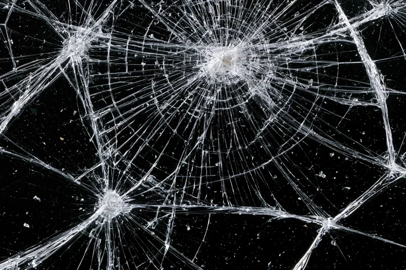Shattered glass pane with radial cracks across black background