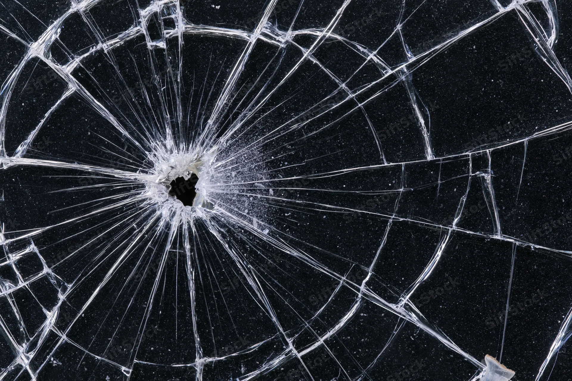 Shattered glass panel with central impact point radiating cracks against dark background