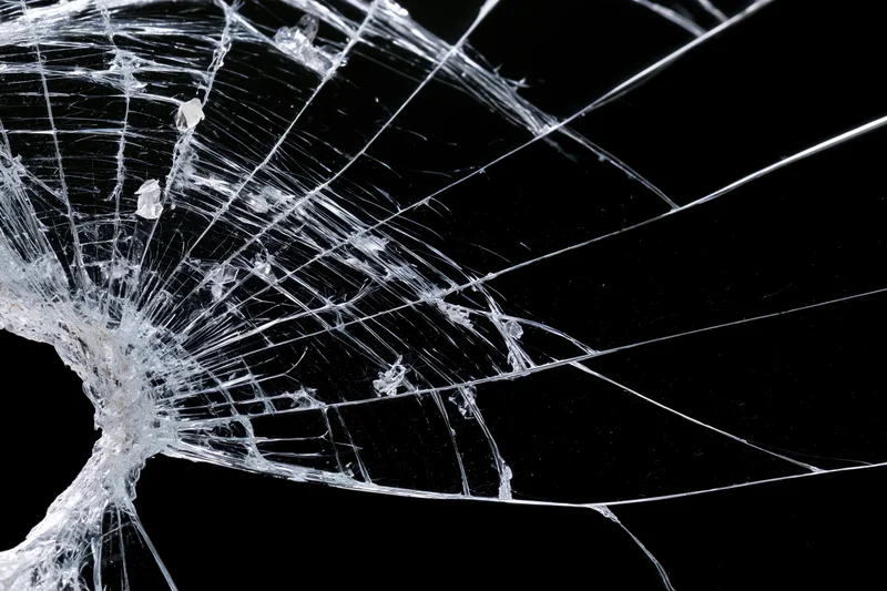 Shattered glass surface with radiating crack lines spreading across black background