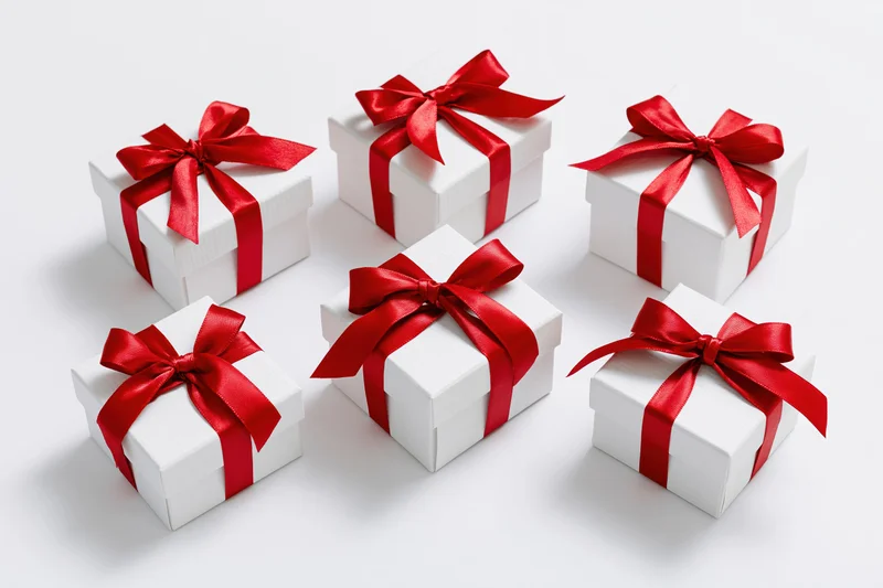 Six white gift boxes with red ribbons arranged in two rows on a white surface