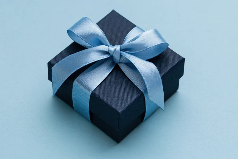 Dark navy gift box with light blue satin ribbon on blue background