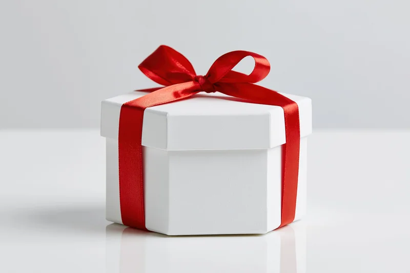 White octagonal gift box tied with red satin ribbon on white surface