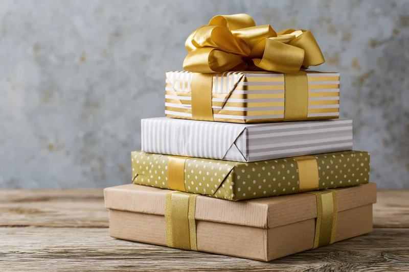 Stack of four wrapped gift boxes piled on a rustic wooden table