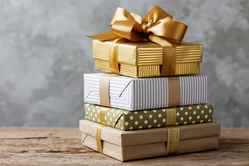 Stack of four wrapped gift boxes piled on a rustic wooden table