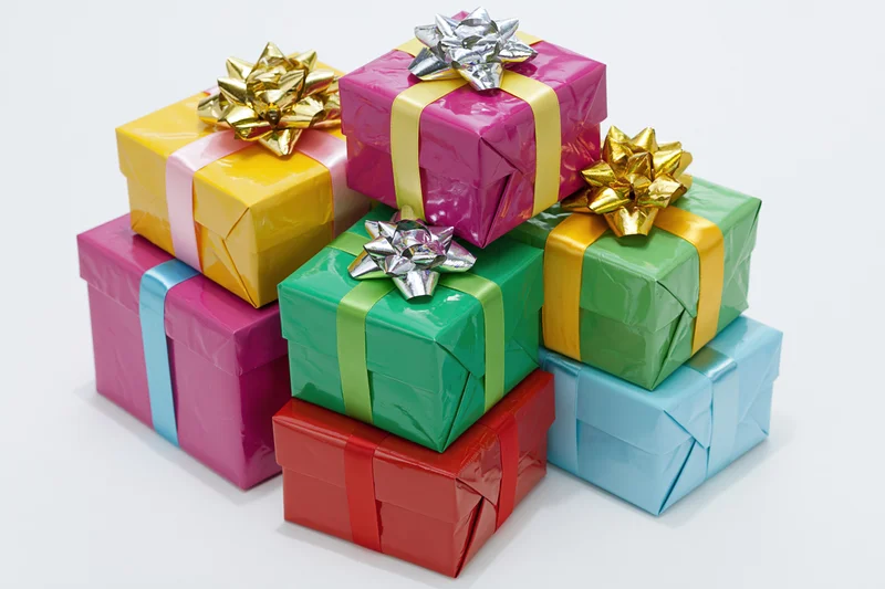 Stack of colorful wrapped gift boxes with ribbons and bows on white background