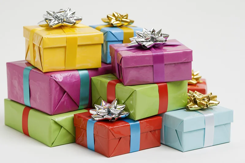 Stack of colorful wrapped gift boxes with ribbons and bows on white background