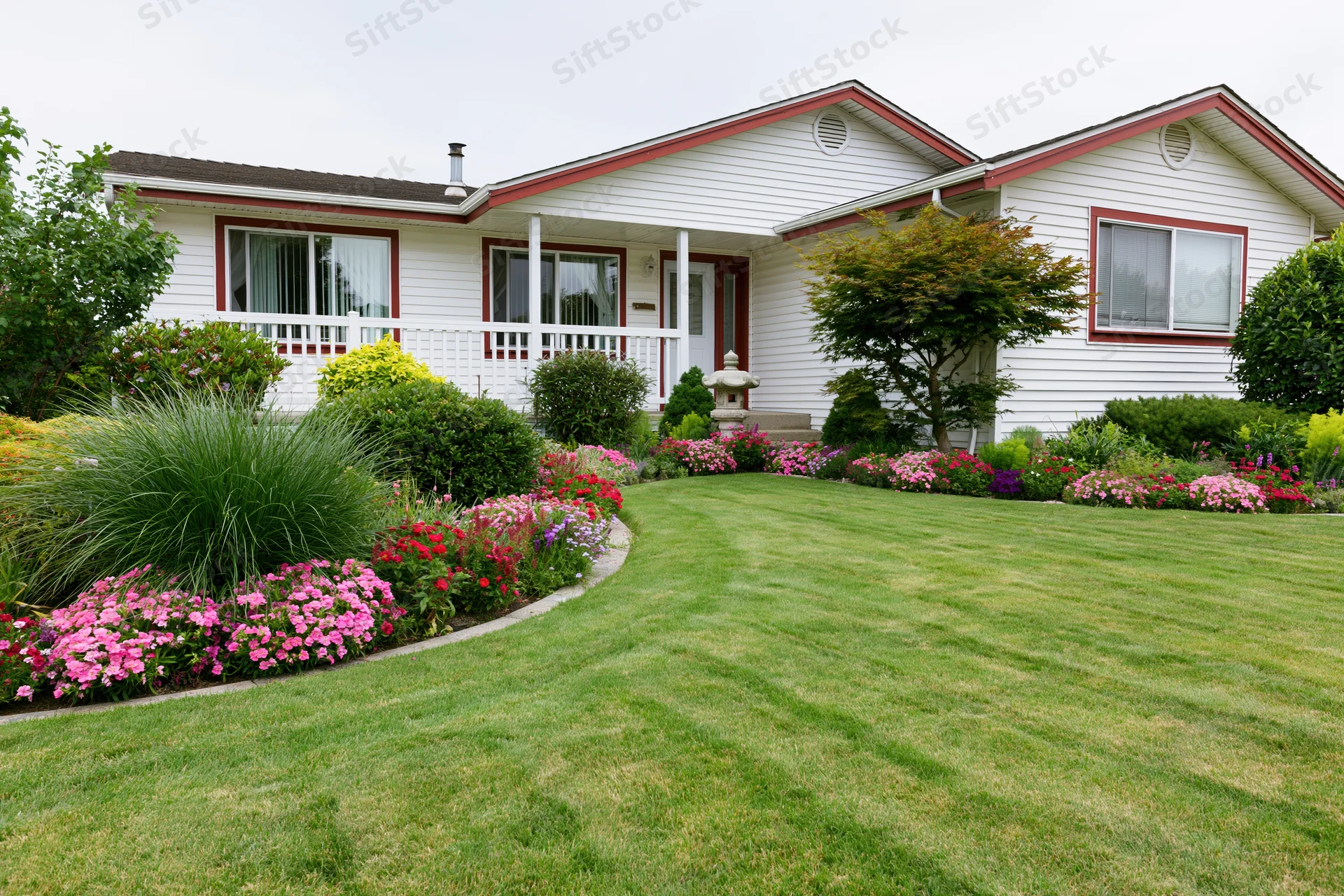 Suburban house with freshly mowed lawn and colorful flower beds along the front yard
