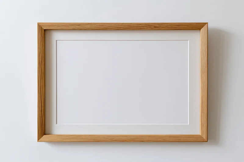 Light oak wooden picture frame with blank white interior hanging on a white wall