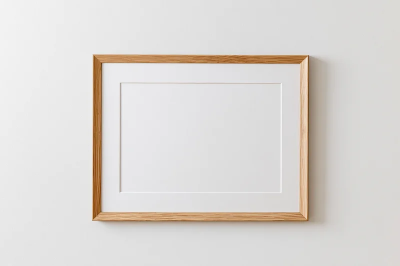 Wooden picture frame with white mat hanging on a plain wall