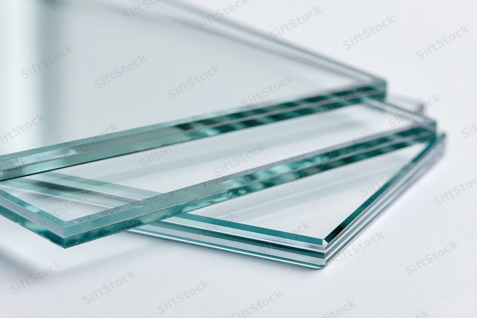 Stacked transparent glass sheets fanned out on a white surface