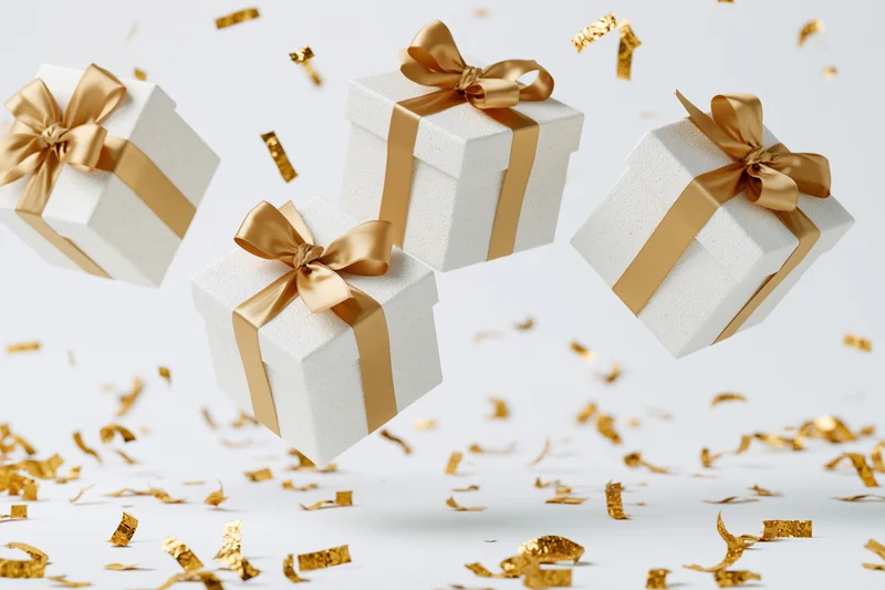 Three white gift boxes gold satin ribbons and bows tumble